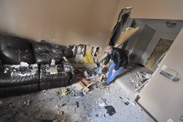 -Messenger photo by Hans Madsen Tim Anderson, of Fort Dodge, looks through the remains of what had been a fish tank that was destroyed early Tuesday morning when a pickup truck crashed into his home in the 1400 block of North 14th Street. 